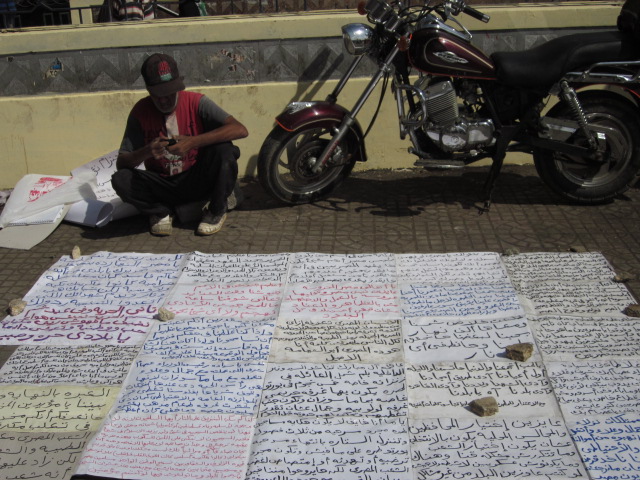 A man sits with signs in tahrir square